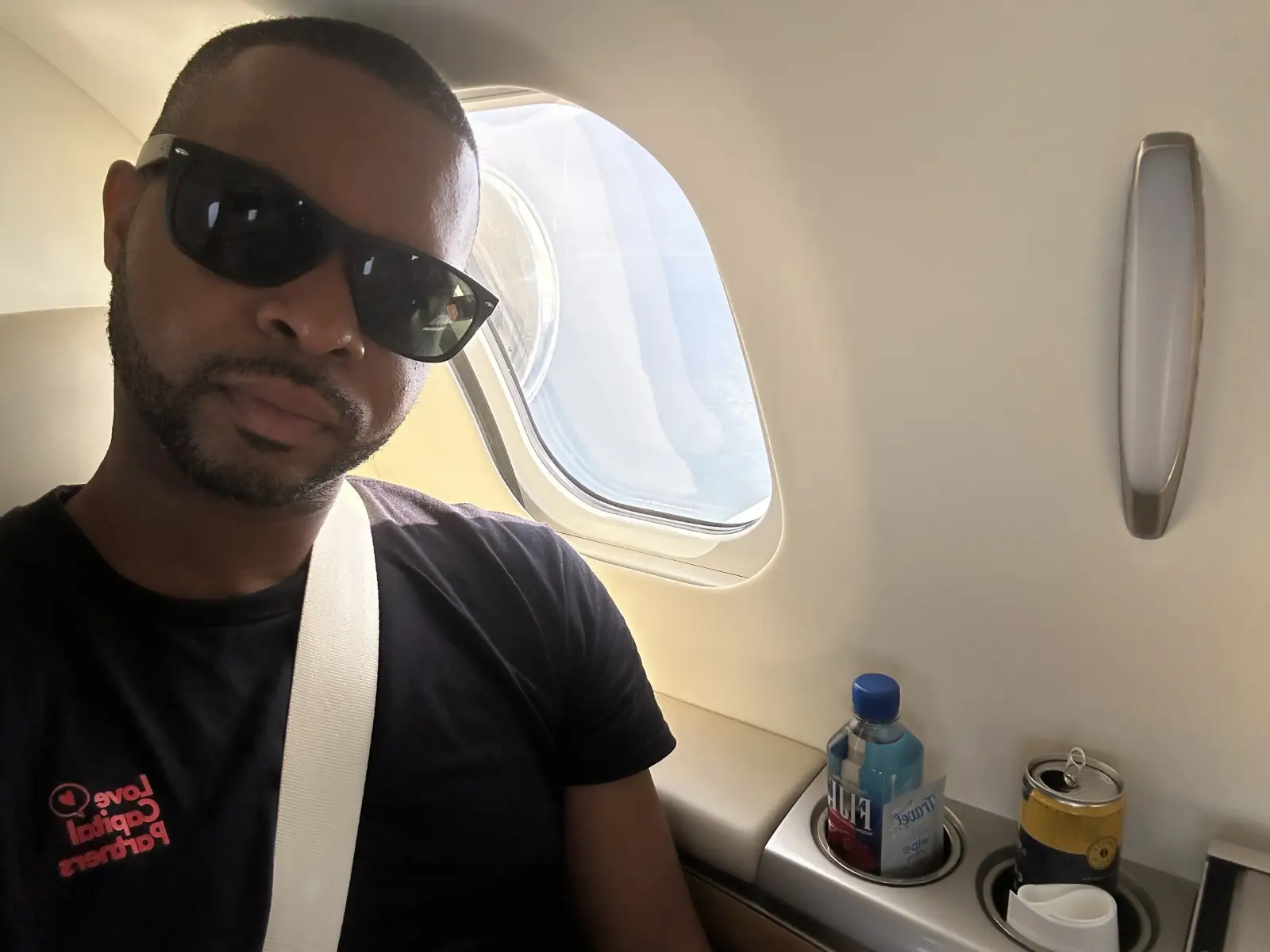 Merrick Lee in sunglasses in a private jet cabin, working on the go