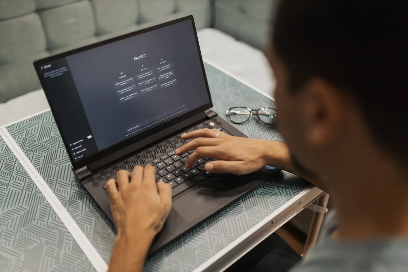 Person typing a request into an AI assistant on a laptop