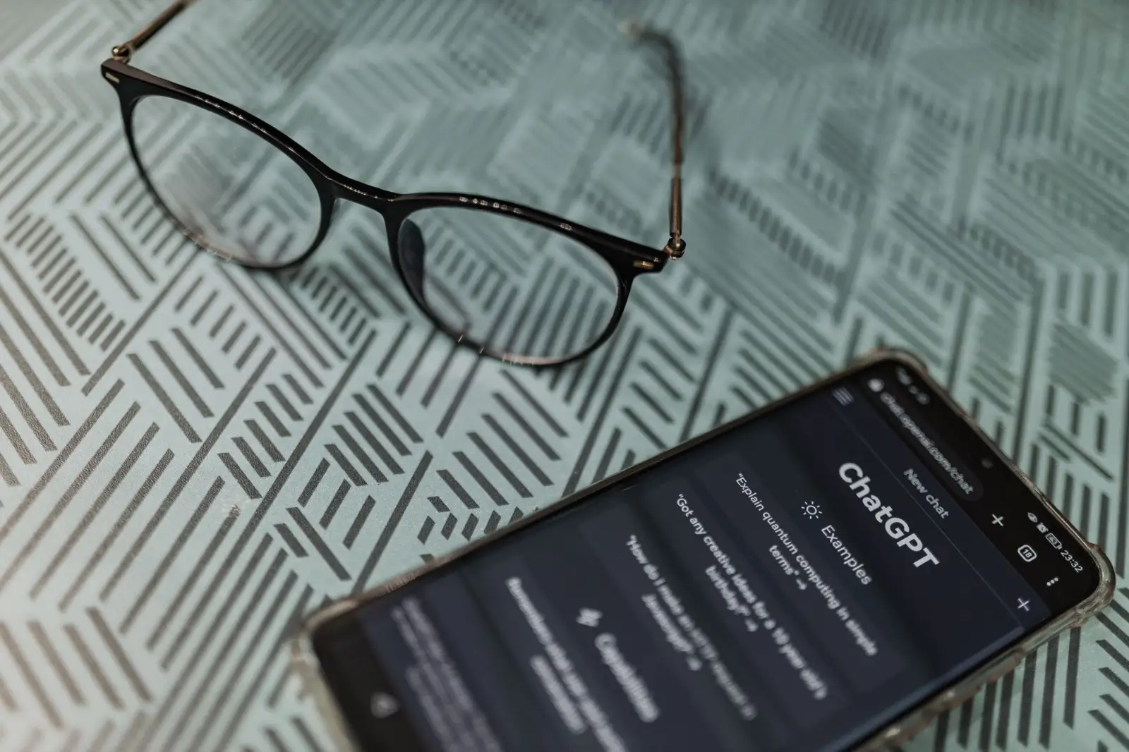Smartphone showing an AI chat app on a table beside eyeglasses