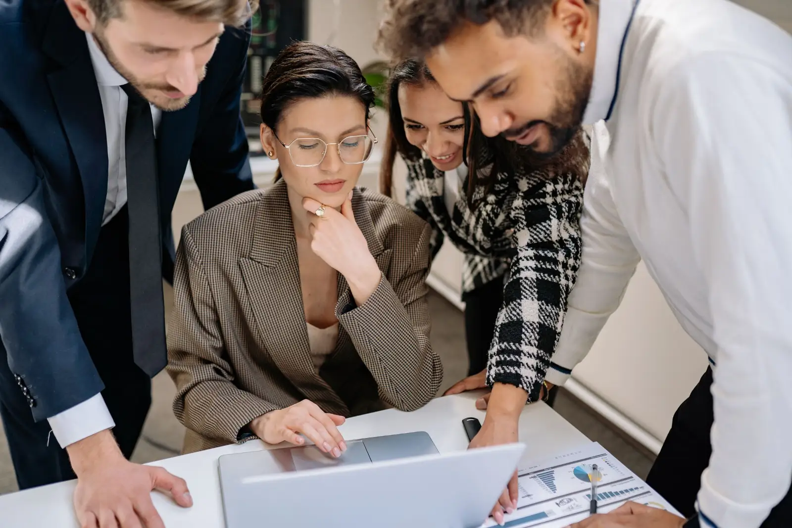 Team gathered around a laptop reviewing pages together before launch