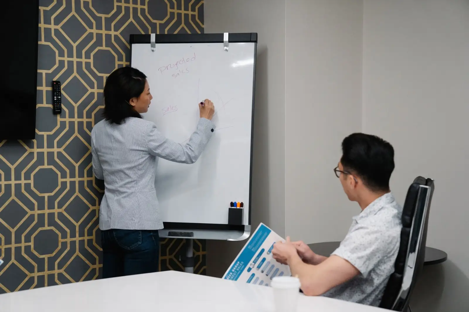 Two colleagues mapping a process on a whiteboard during a meeting