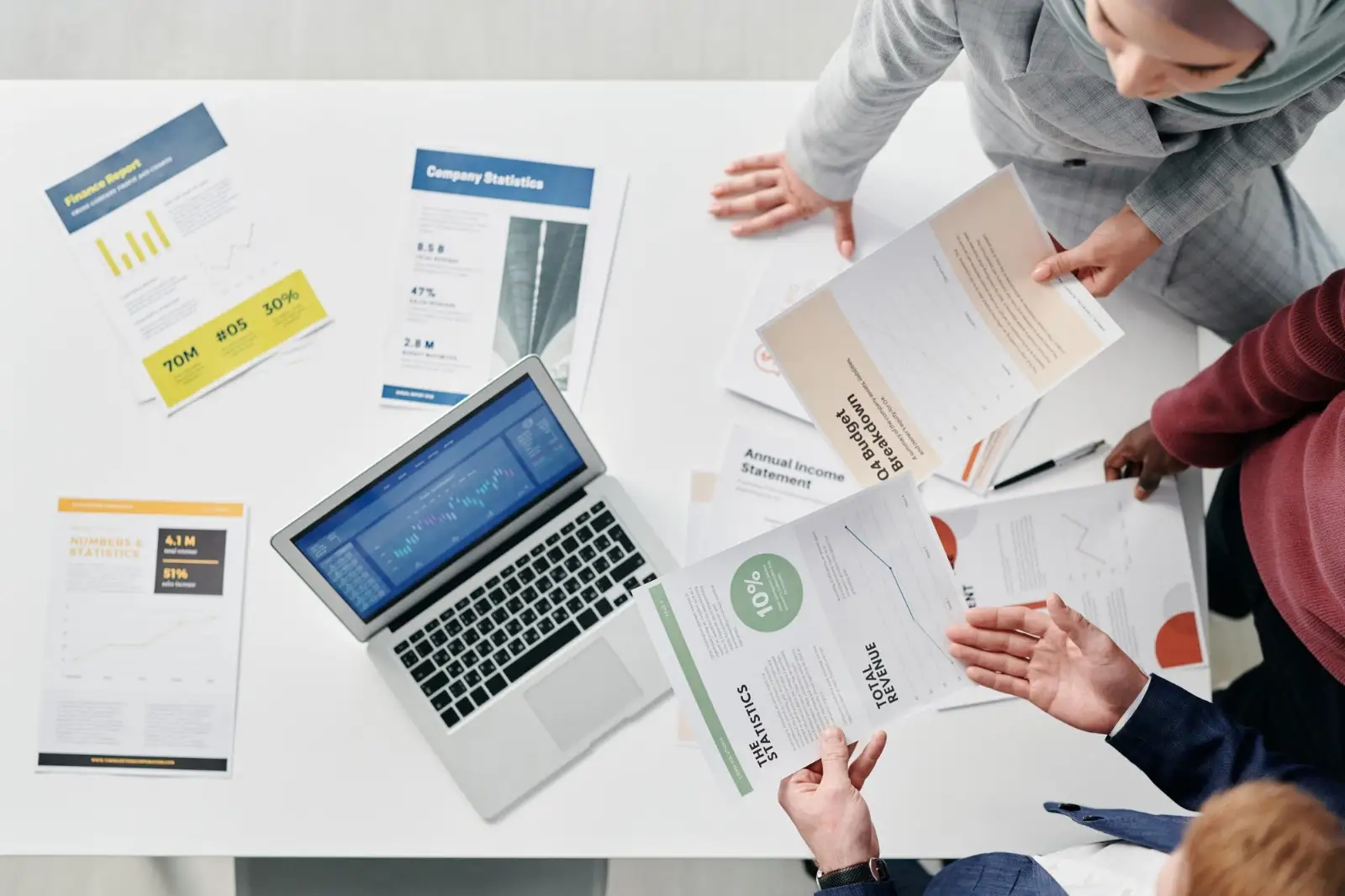 Team at a table comparing printed reports with a laptop